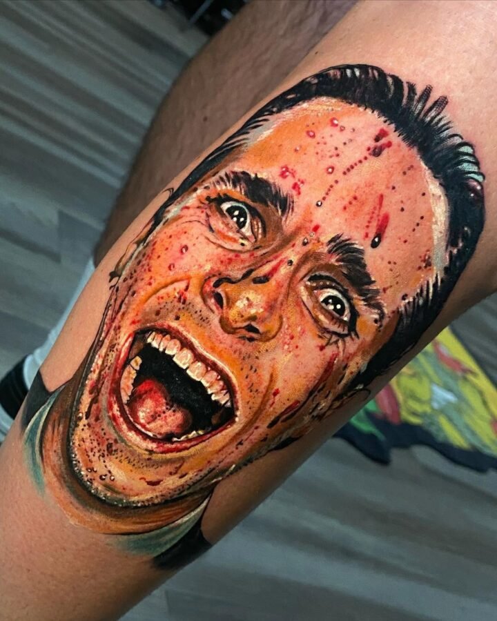 Colour realism portrait tattoo of a shouting face on the upper arm