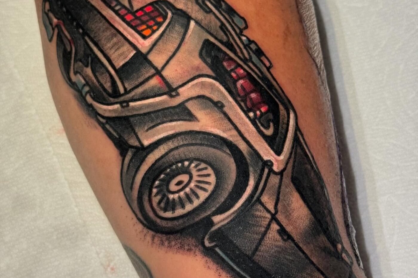 Black and grey realism tattoo of a DeLorean car on the calf