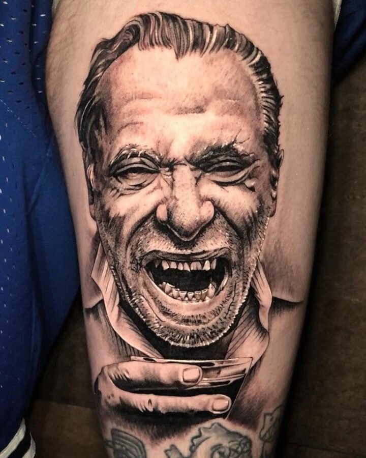 Black and grey photo-realistic portrait tattoo of a laughing man on the forearm