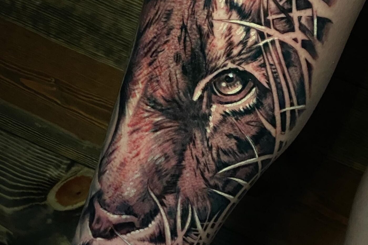 Black and grey lion tattoo with textured background on the forearm