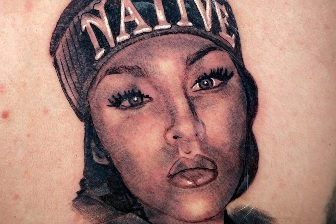 Black and grey portrait tattoo of a woman in a cap on the chest