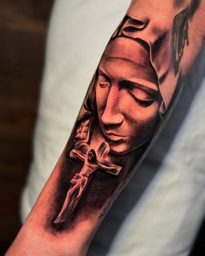 Black and grey tattoo of the Pieta with a crucifix on the forearm